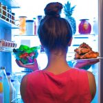 A young woman standing in front of the refrigerator