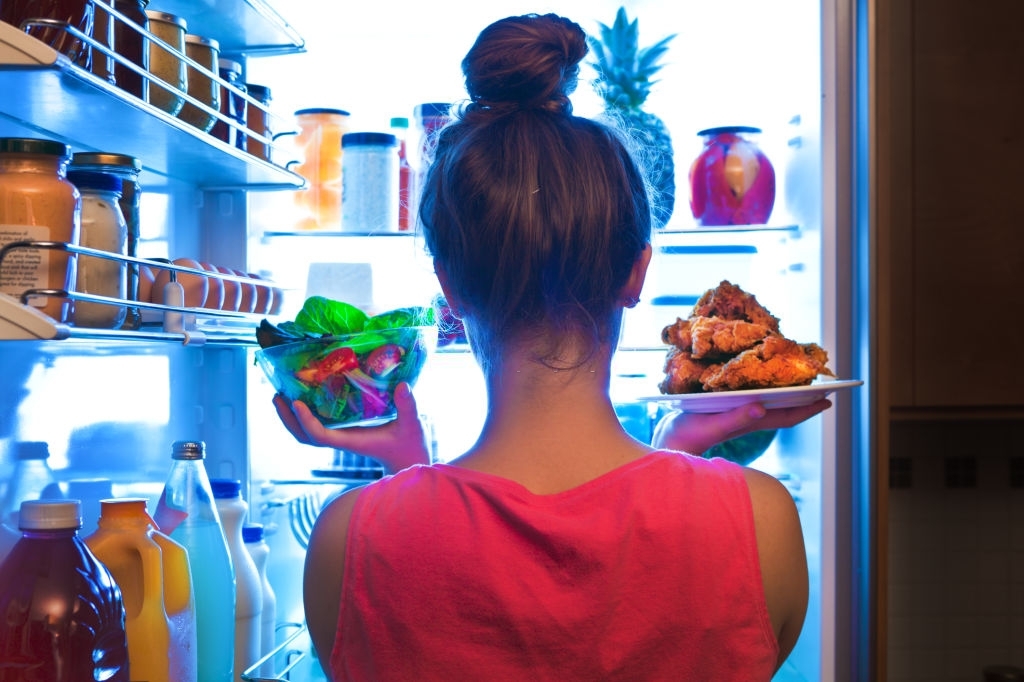 A young woman standing in front of the refrigerator